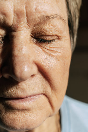 Close-up of elderly caucasian woman with closed eyes in natural lightの写真素材