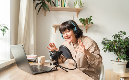 Woman enthusiastically podcasting from home studioの写真素材