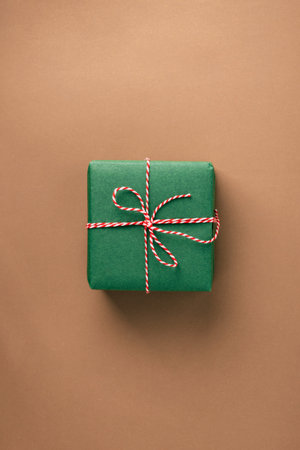 Christmas gift with a bow on a beige background, top view, minimalist, zero-waste conceptの写真素材