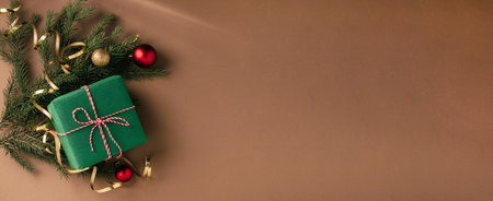 Christmas gift, fluffy fir branches, golden sparkling streamers and Christmas tree decorations, beige backgroundの写真素材