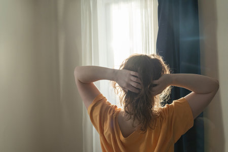 Woman stretching in morning light near windowの写真素材