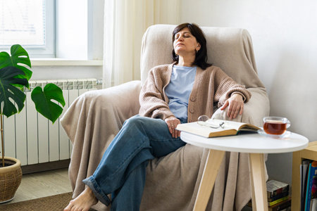 Woman resting comfortably at home with tea and book