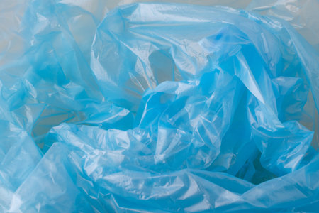 Crumpled blue plastic material forming an abstract background texture. Showing translucent, synthetic, and reusable plastic packagingの写真素材