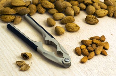 Almonds and nutcracker on wood slab