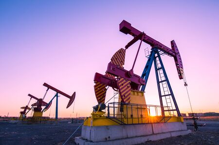 Oil pumps are running in the sunset at the oil field. On the Bohai coast of China.の写真素材