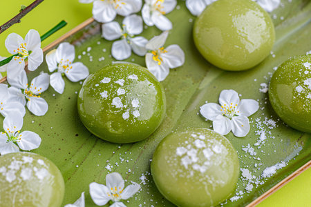 Green tea mochi with jasmine flowers on green plateの素材