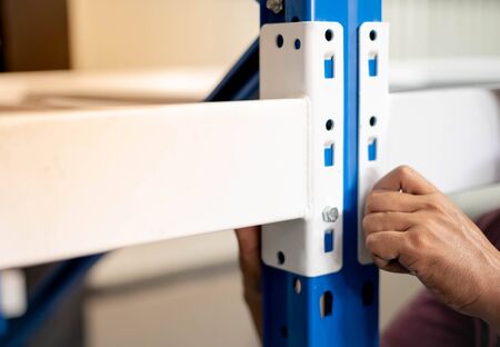 Male hand screw a knot to assembling the metal rack  in warehouse or storage and shelves for...