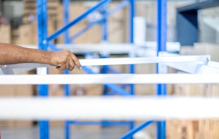 Male hand preparing to assembling the metal rack  in warehouse or storage and shelves for cardboard...