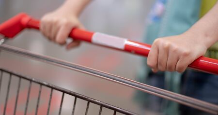 Female hand pushing shopping trolleys in Supermarket Walking through the Aisle preparing food for the hoarding food coronavirus (COVID-19) pandemic crisis.の写真素材