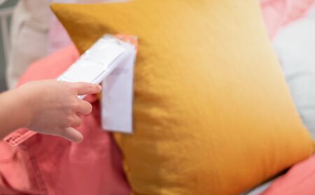 Female hand holding the price tag and looking the price for decision about the quality  of the pillow and choose the color at the department store.の写真素材