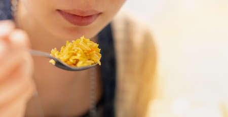The Asian girl hand holding spoon and eating the egyptian curry fried rice food at the restaurant,...