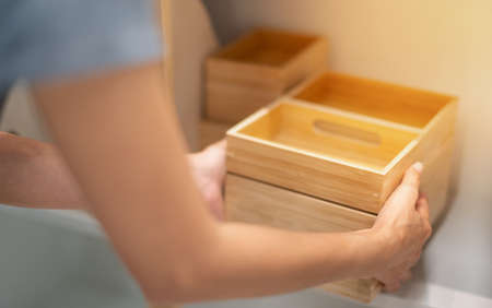 Female hand holding the wood box for arrange on the shelf for convenience to use.の写真素材