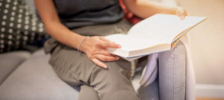 Female hand holding notebook and reading book for relax and the knowledge while sitting on the sofa...