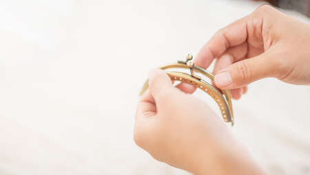 The female hand choosing a purse clasp that showing the perforated metal frame with the angled bead fastener. The accessories for a purse. For hobby and leisure concept.の写真素材