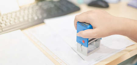 Close-up female hand puts a stamping document for agreement, company secretary, official documents working at the office.の写真素材