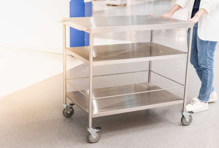 Female hand pushing the stainless steel food trolley cart to move a lot of parcels.