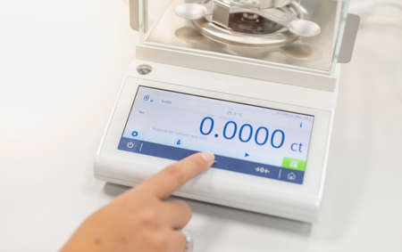 The female hand pushes the digital Hydrostatic Weighing Balance to examine the specific gravity to...