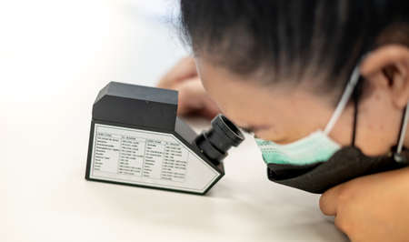 The Gemologist examing the precious stone with the refractometer to separate the type of stone.