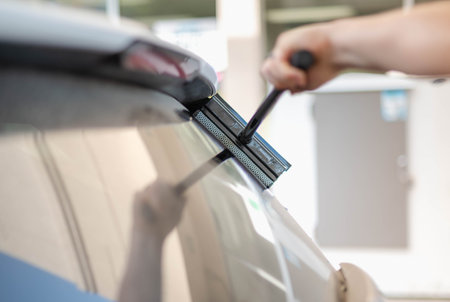 Mature male worker cleaning car windshield with the sponge mop.の写真素材