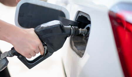 Female worker hand holding nozzle fuel fill oil into car tank at pump gas station, For the concept transportation power business technology conceptの写真素材