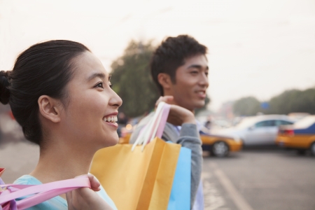 Young couple walking down the street with shopping bags in Beijing, close-upの写真素材