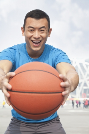 Portrait of smiling young man holding a basketball, Beijingの写真素材