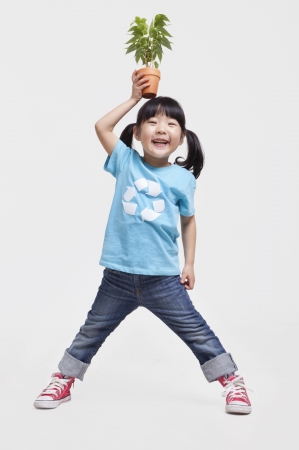 Little girl holding potted plant above her head, studio shotの写真素材