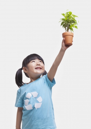 Little girl holding potted plant above her head, studio shotの写真素材