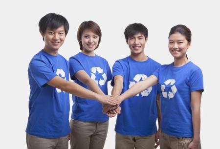 Four young people in recycling t-shirts with hands together, studio shotの写真素材