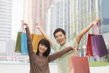 Portrait of young couple posing with shopping bags in hands, Beijing, China の写真素材