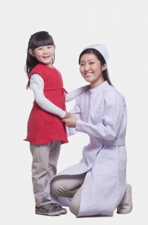 Portrait of nurse and child, kneeling, studio shotの写真素材