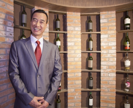 Smiling Businessman Standing by Wine Bottlesの写真素材