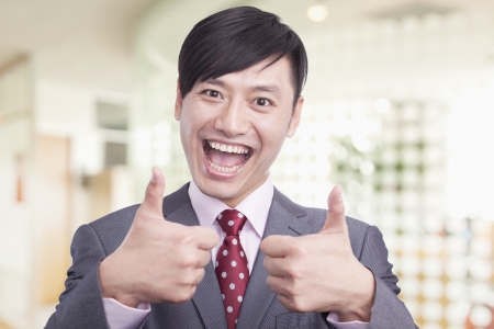 Young businessman giving the thumbs up sign, portraitの写真素材