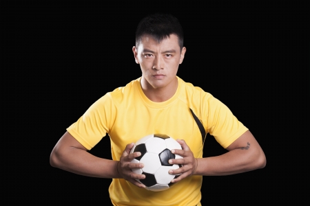 Footballer player holding ball to chest, black backgroundの写真素材