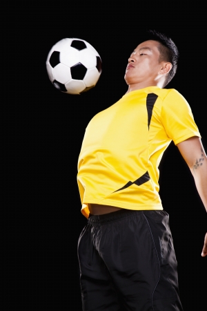 Footballer chesting ball, black backgroundの写真素材
