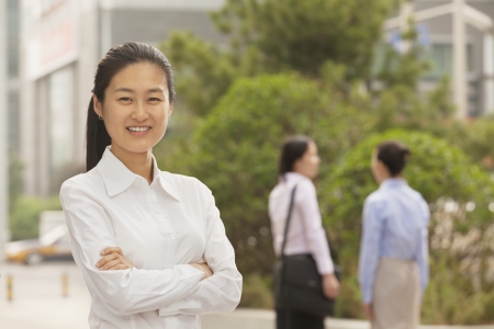 Portrait of smiling young businesswoman with arms crossed, Beijingの写真素材