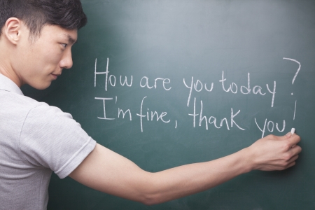 Young man writing English sentences on the blackboardの写真素材