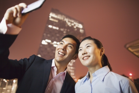 two business people smiling and taking a picture with the phone の写真素材