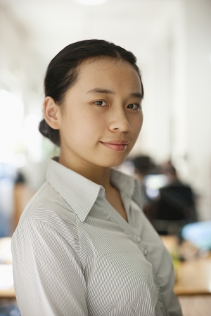 Young woman standing in the office, portraitの写真素材