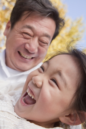 Grandfather and Granddaughter Playing in the Parkの写真素材