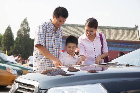 Family standing next to the car and looking at the mapの写真素材