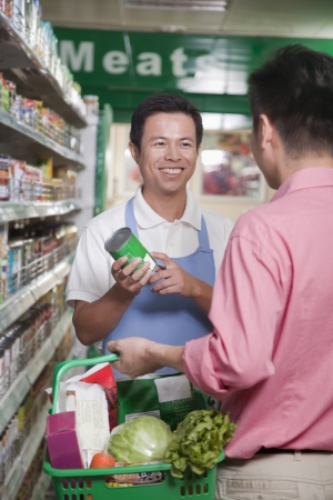 Sales clerk assisting man in supermarket, Beijingの写真素材