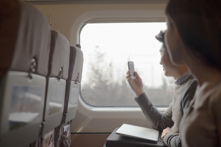Young man sitting on a train taking a photo out the window