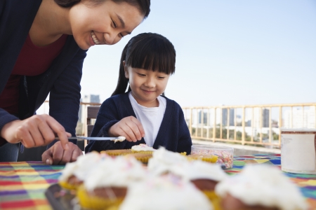 Mother and daughter decorating cupcakesの写真素材