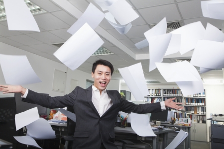 White-collar worker throwing white sheets in air in officeの写真素材