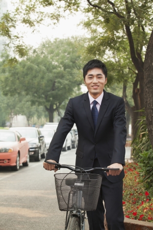 Young businessman holding a bicycle on a city street in Beijingの写真素材
