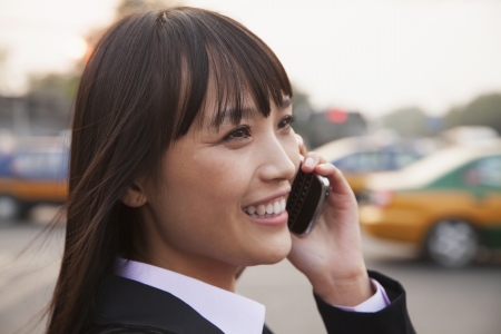 Young businesswoman using the phone outside on the street in Beijing, close up portraitの写真素材