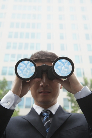 Young Businessman Using Binoculars and Looking into the Distanceの写真素材