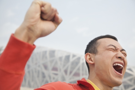 Determined young man with fist in the air, close-up, Beijingの写真素材