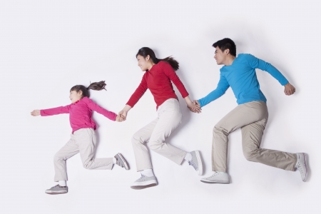 Family holding hands and imitating running, studio shotの写真素材